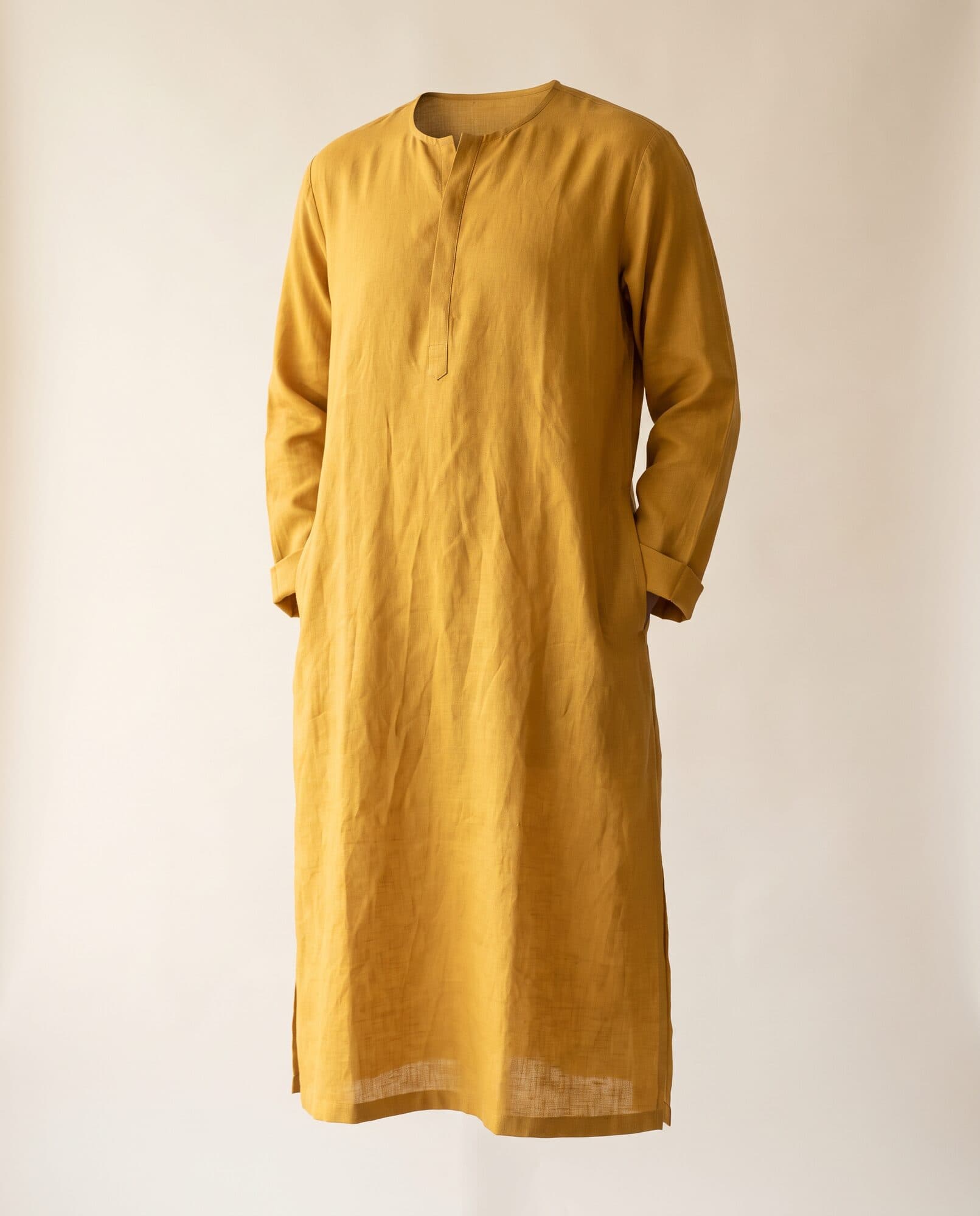Mustard yellow linen kurta on invisible mannequin with turned cuffs